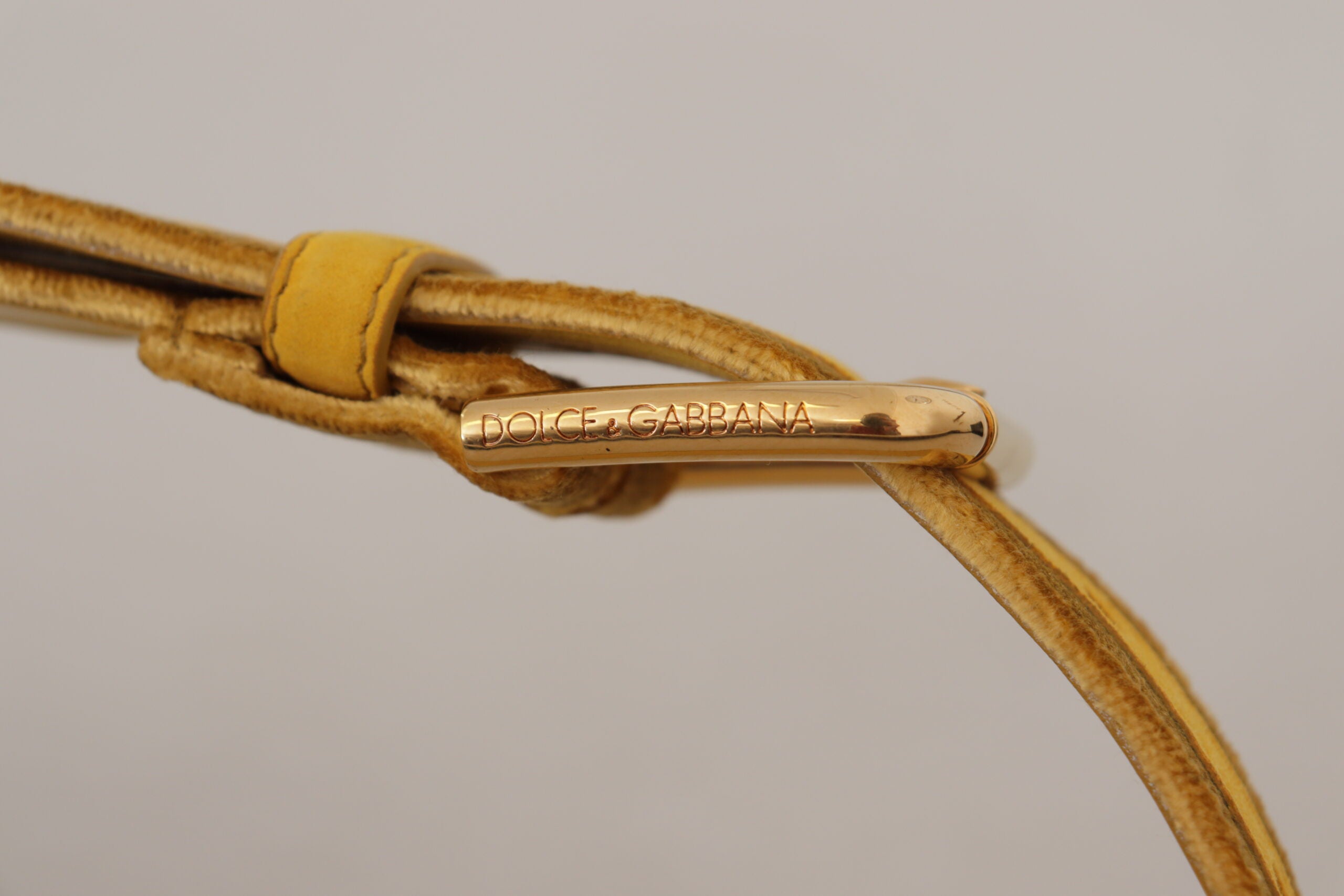 Gele fluwelen riem met gouden metalen logo en gegraveerde gesp