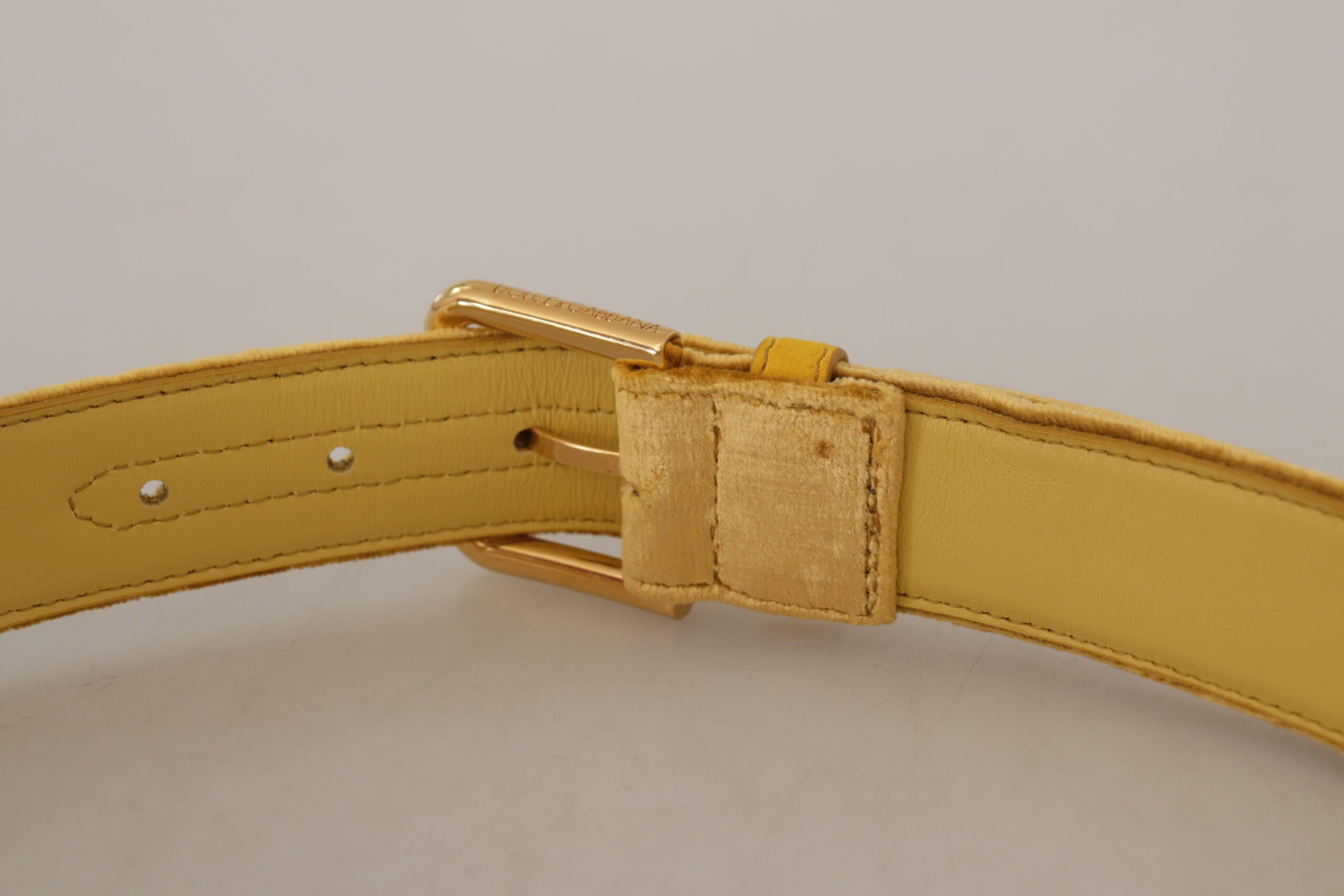 Gele fluwelen riem met gouden metalen logo en gegraveerde gesp
