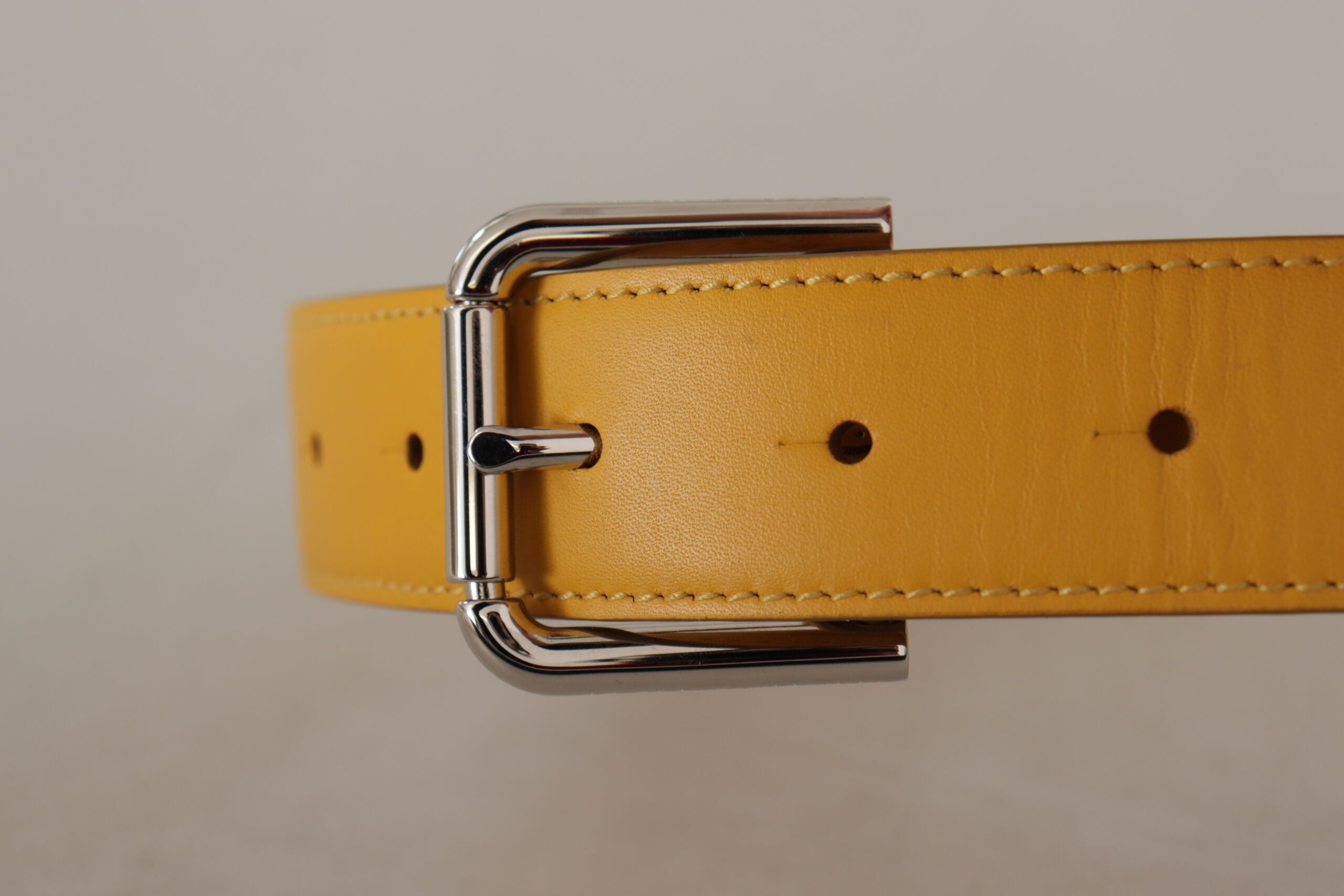 Gele leren riem met zilveren logo en metalen gesp