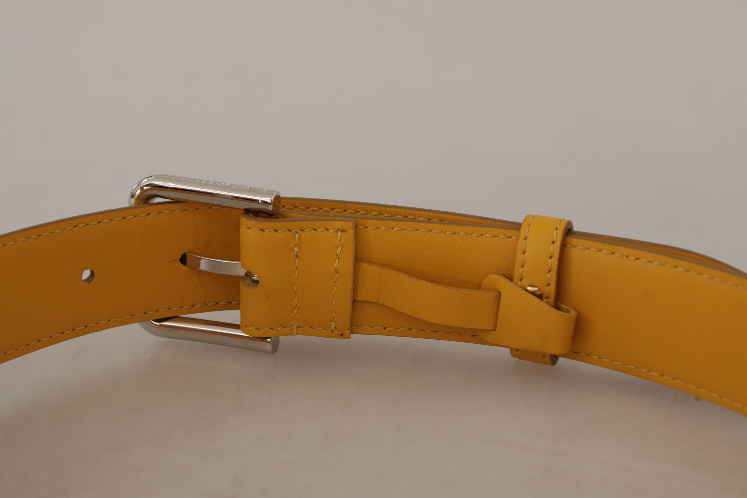 Gele leren riem met zilveren logo en metalen gesp