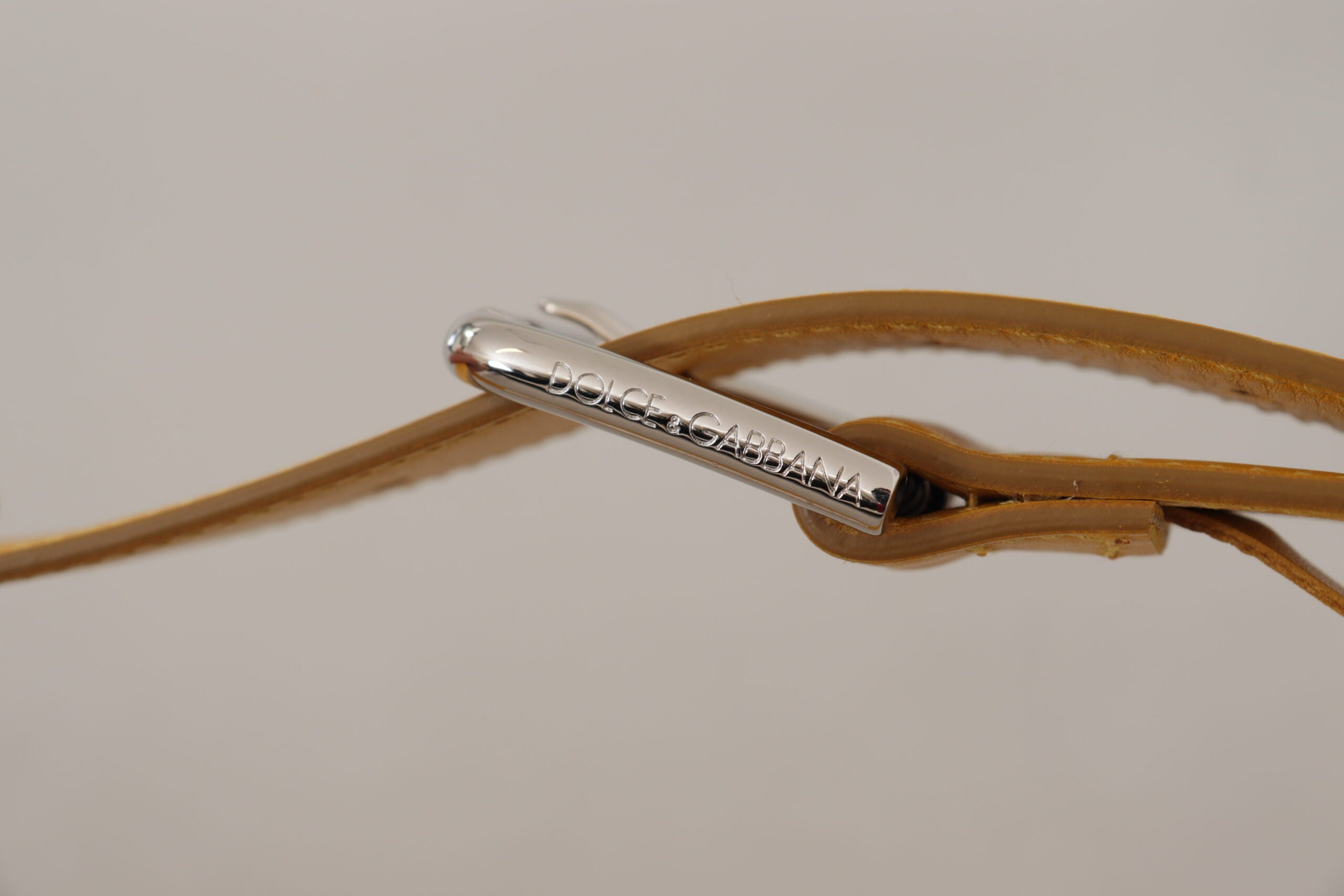 Gele leren riem met zilveren logo en metalen gesp