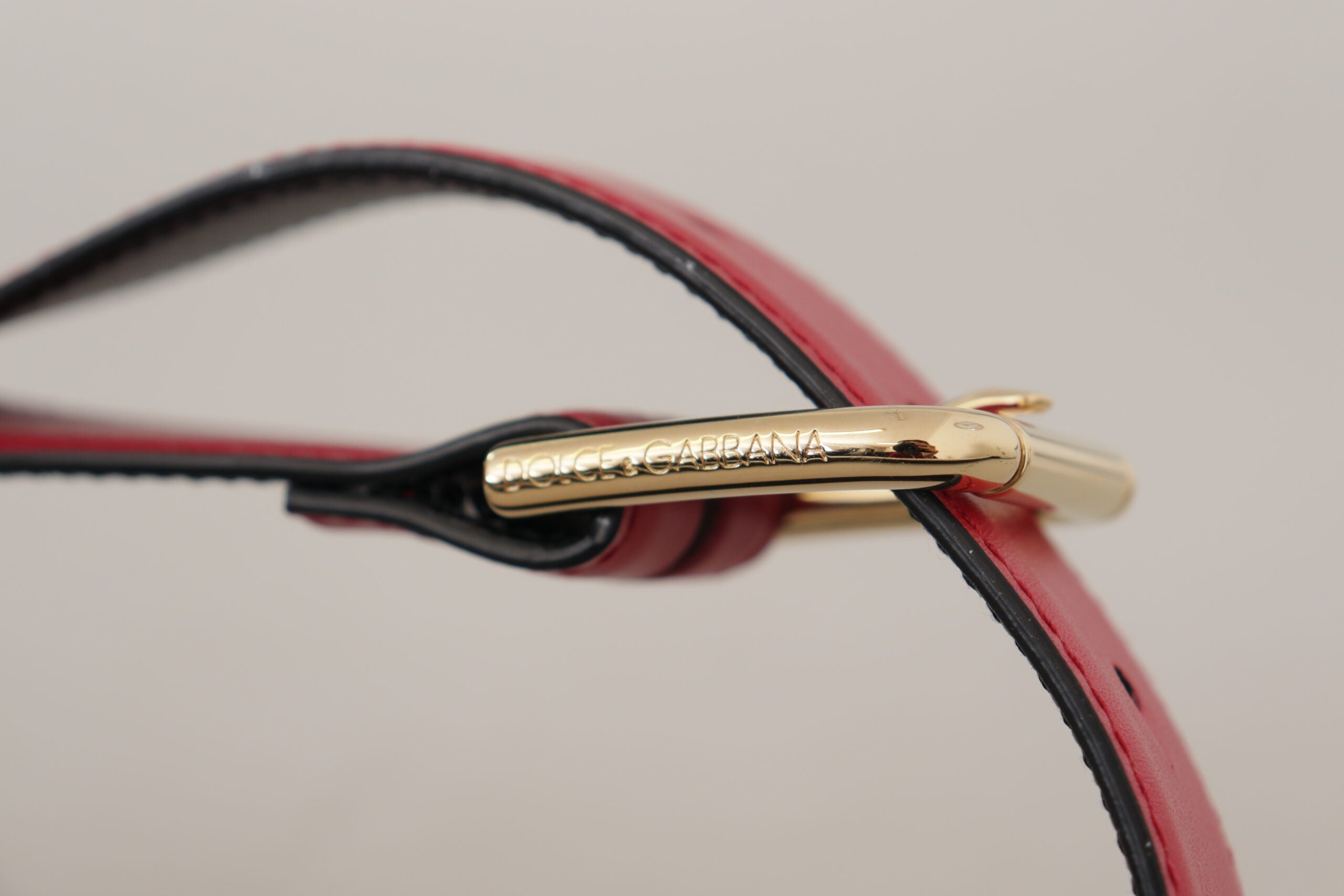 Rode kalfsleren riem met gouden logo en metalen gesp
